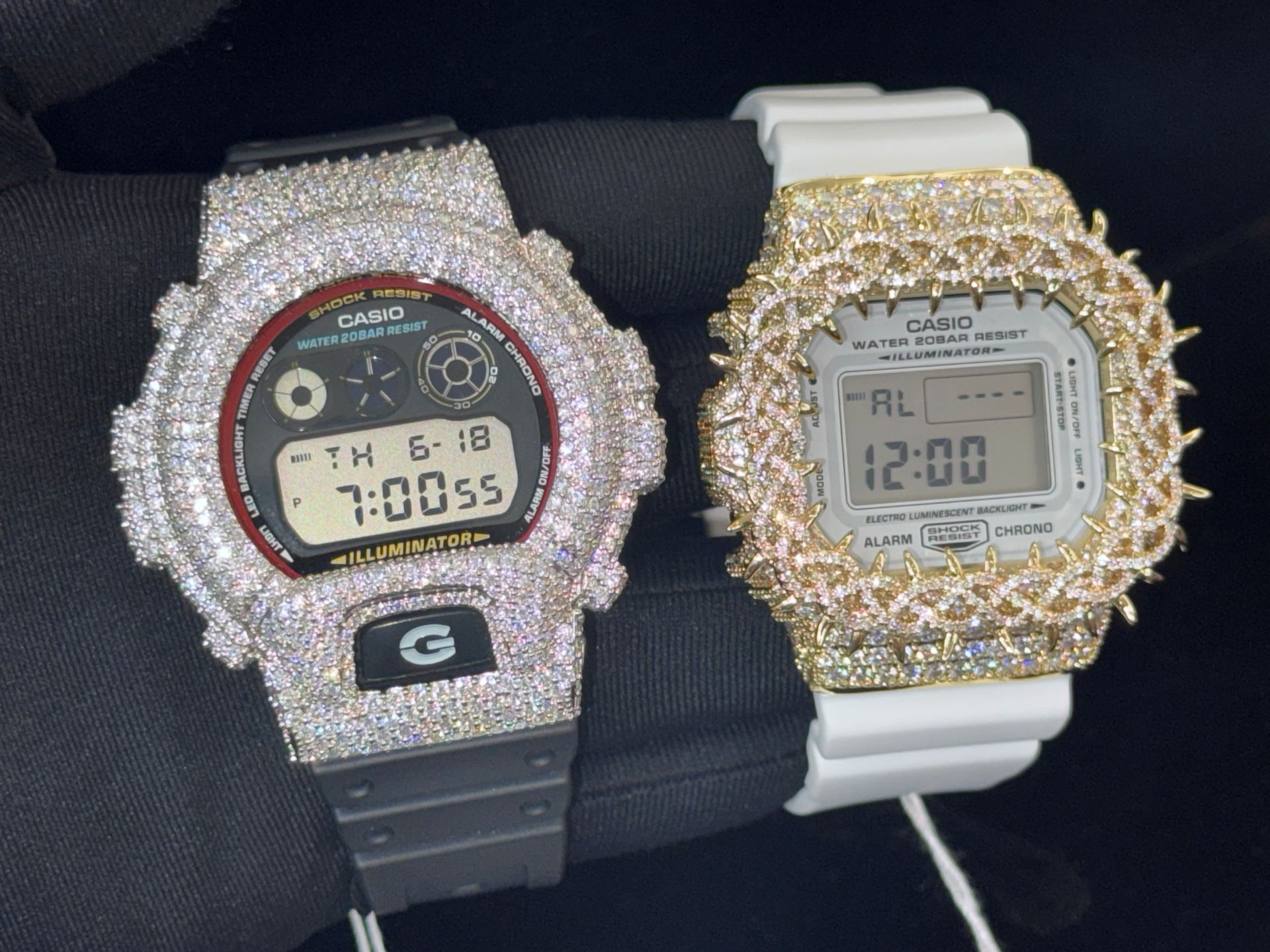 Two glittering digital watches, one black and one white, displayed side by side on a dark surface