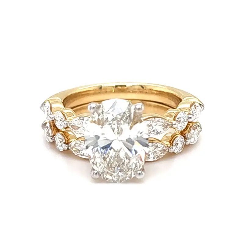 Gold ring with a large round diamond and smaller side stones on a white background