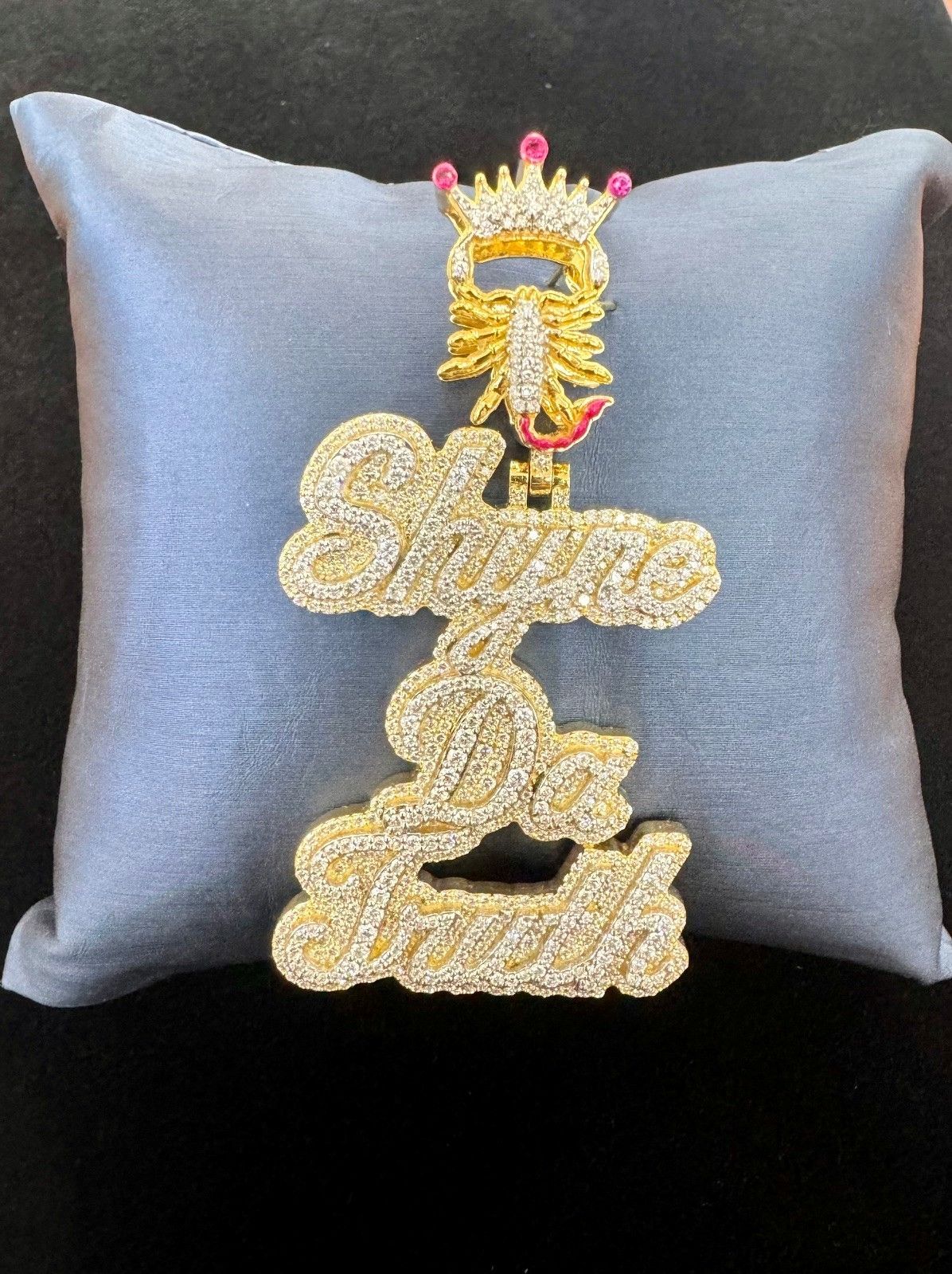 Gray pillow with a jeweled gold decorative emblem on a black background