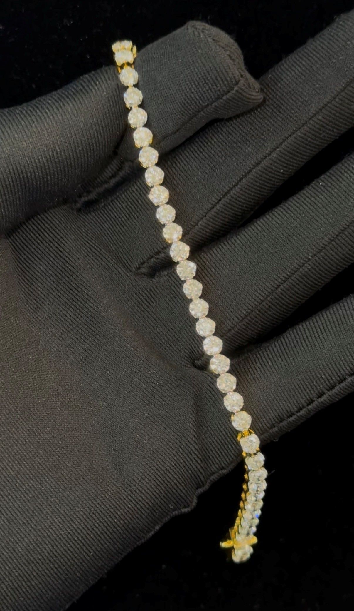 Small pearl beaded bracelet with gold accents held against a black gloved hand