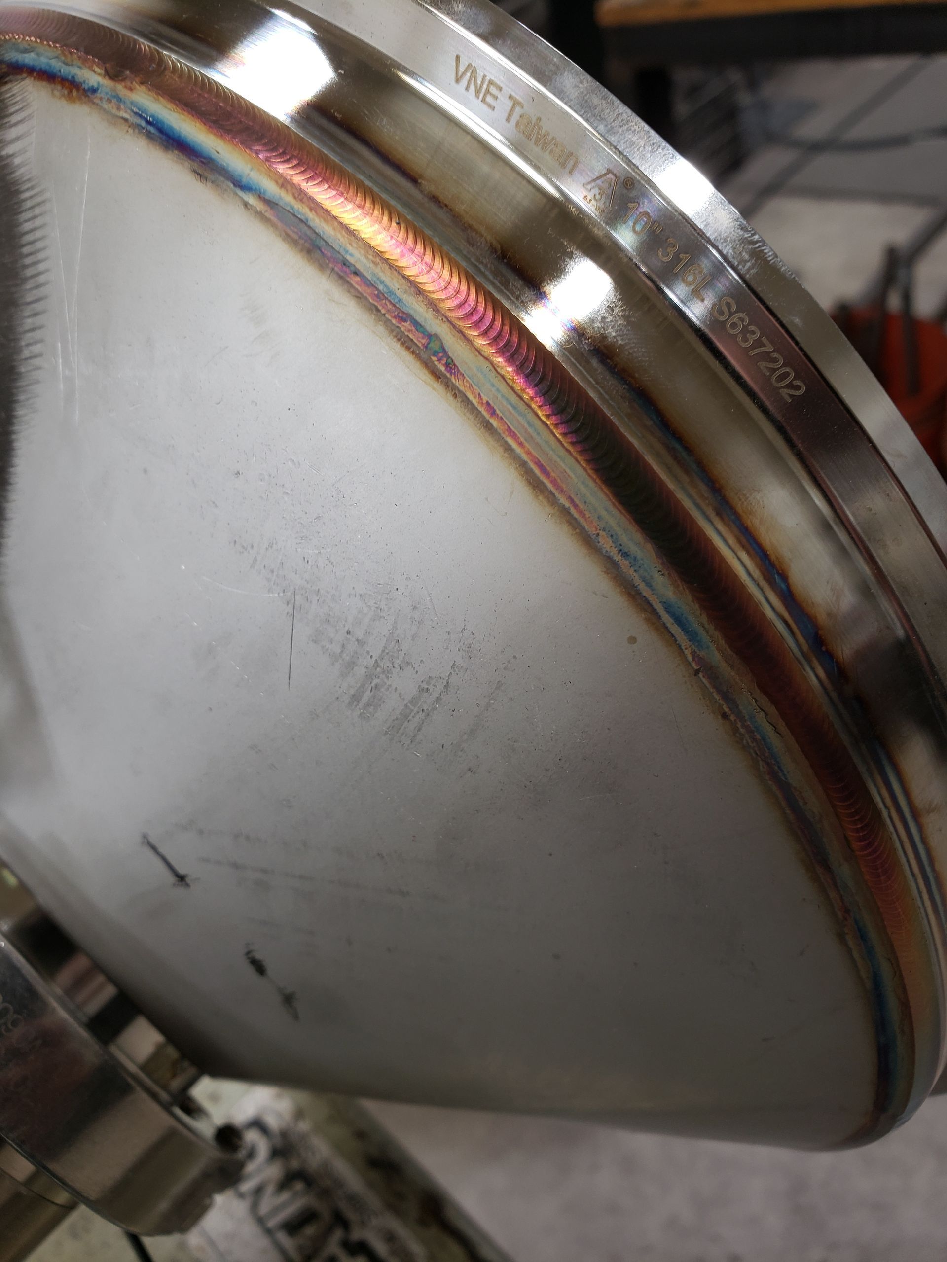 Close-up of a stainless steel welded metal part, showing the welds and the metal's surface.