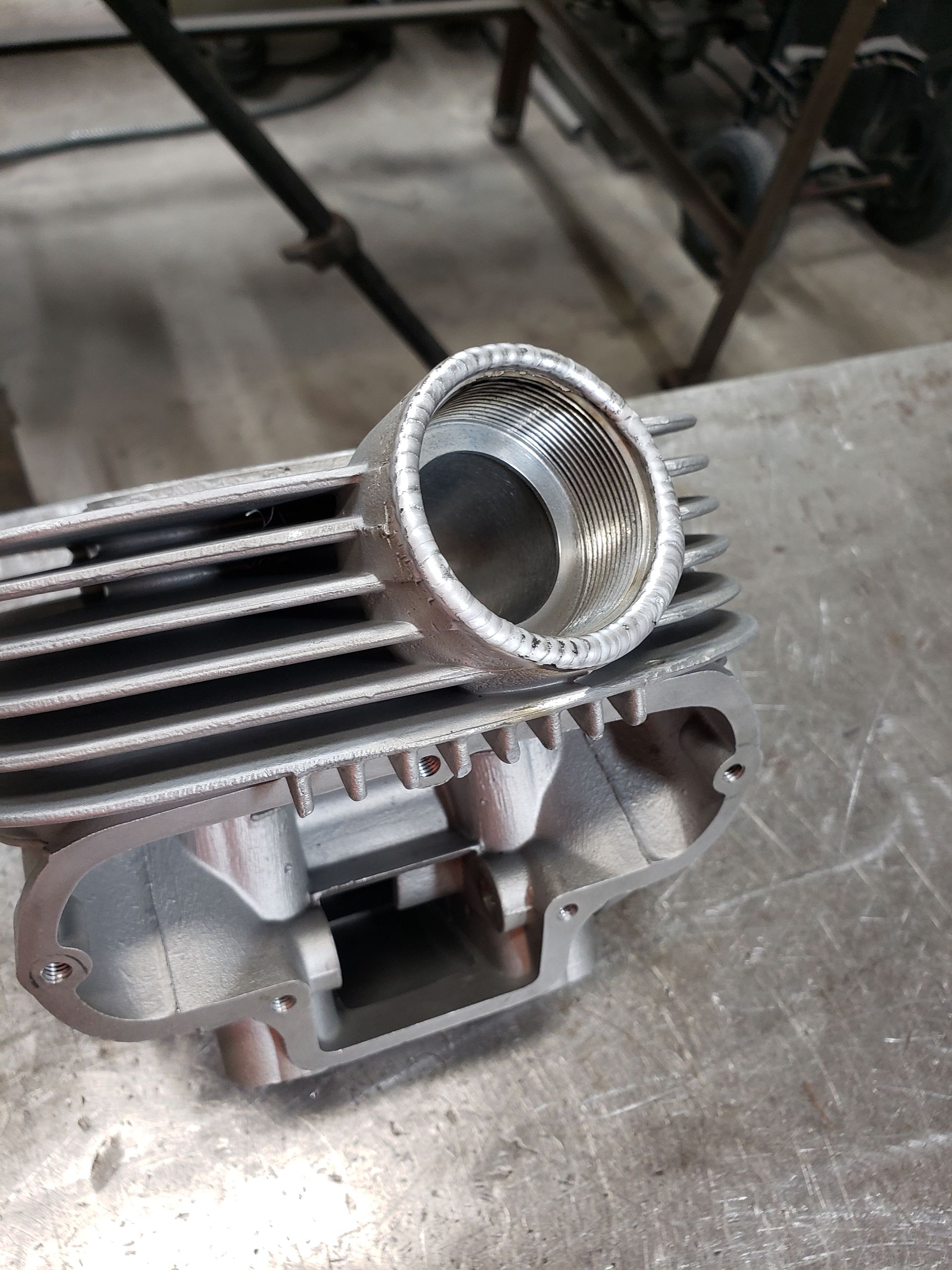 Aluminum motorcycle cylinder head, silver with cooling fins, open port.
