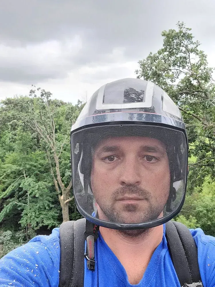 A man wearing a helmet and a backpack is taking a selfie.
