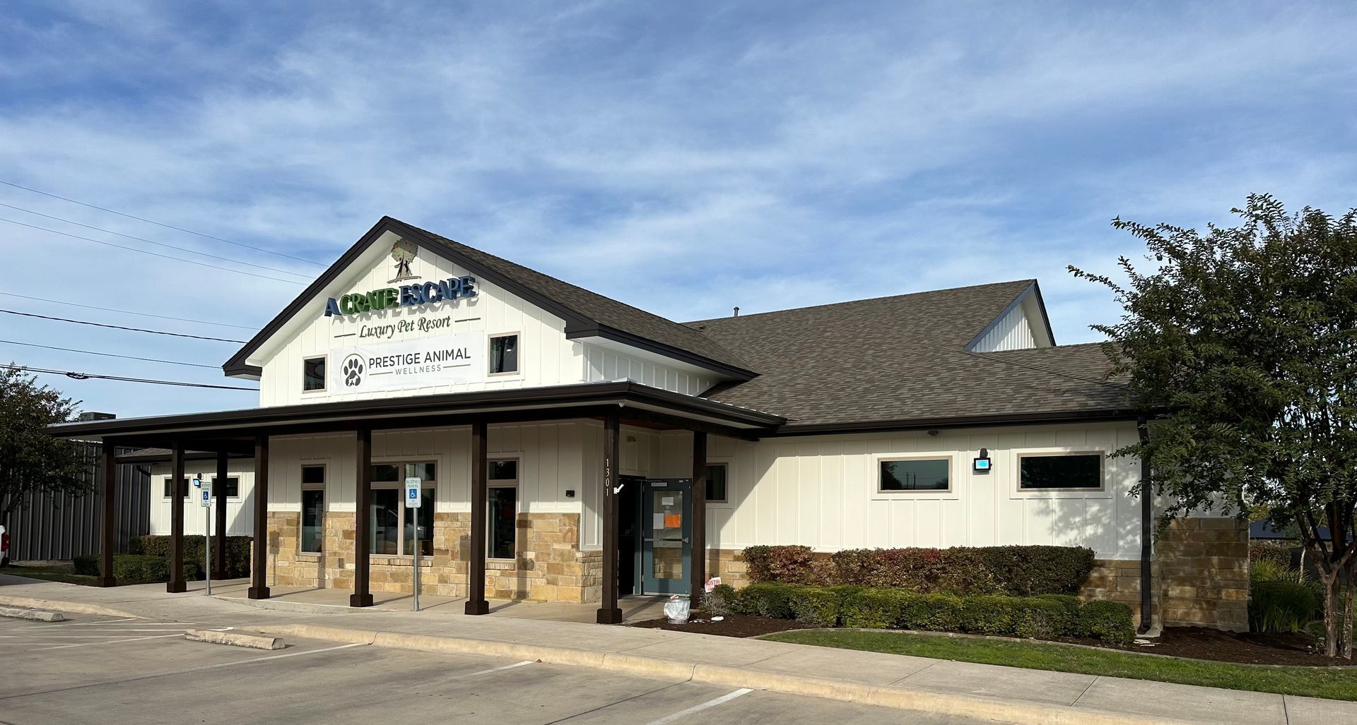 A large white building with a gray roof and a parking lot in front of it.