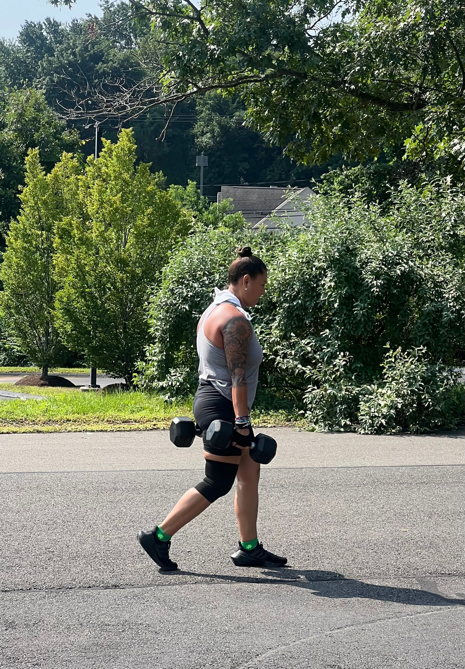 A man is walking down the street with a dumbbell in his hand.