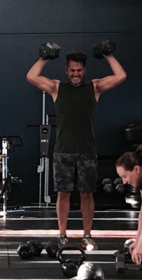 A man is lifting dumbbells in a gym.