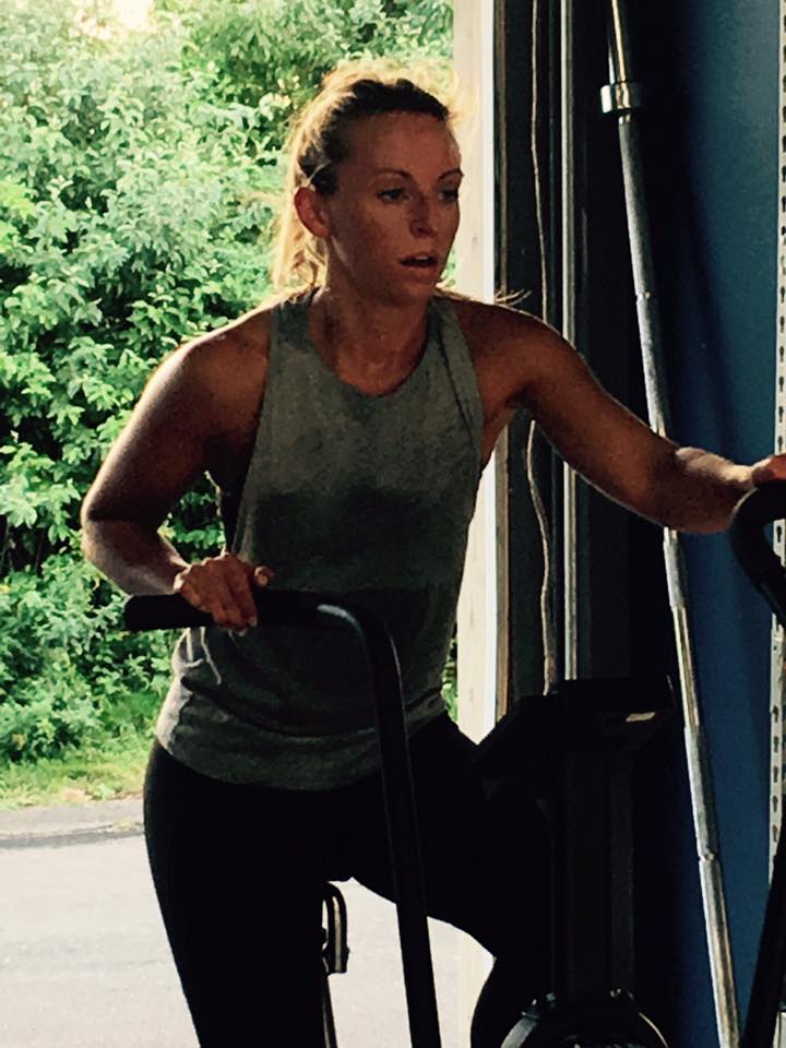 A woman is riding an exercise bike in a gym.