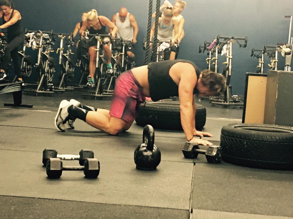 A group of people are doing push ups in a gym