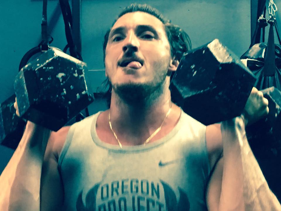 A man in an oregon project shirt is lifting dumbbells