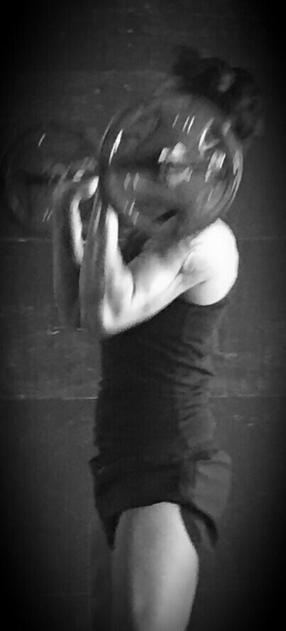 A black and white photo of a woman holding a weight plate.