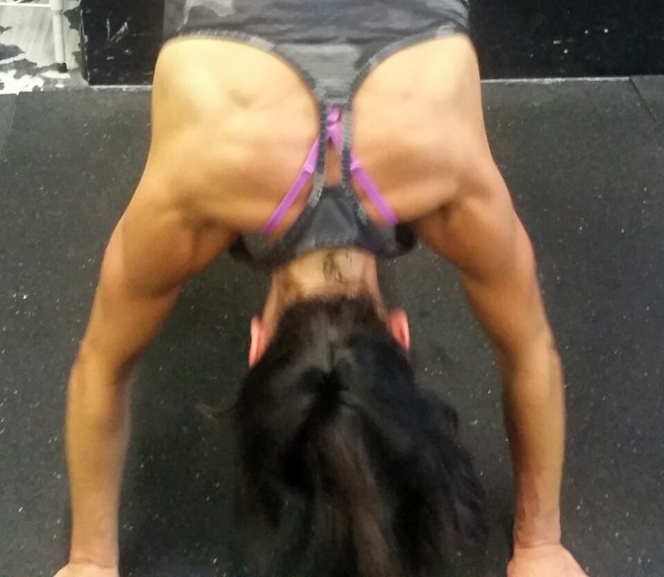 A woman is doing a handstand in a gym