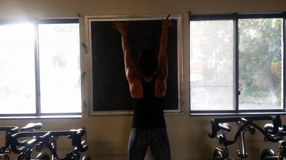 A woman is standing in front of a blackboard in a gym.