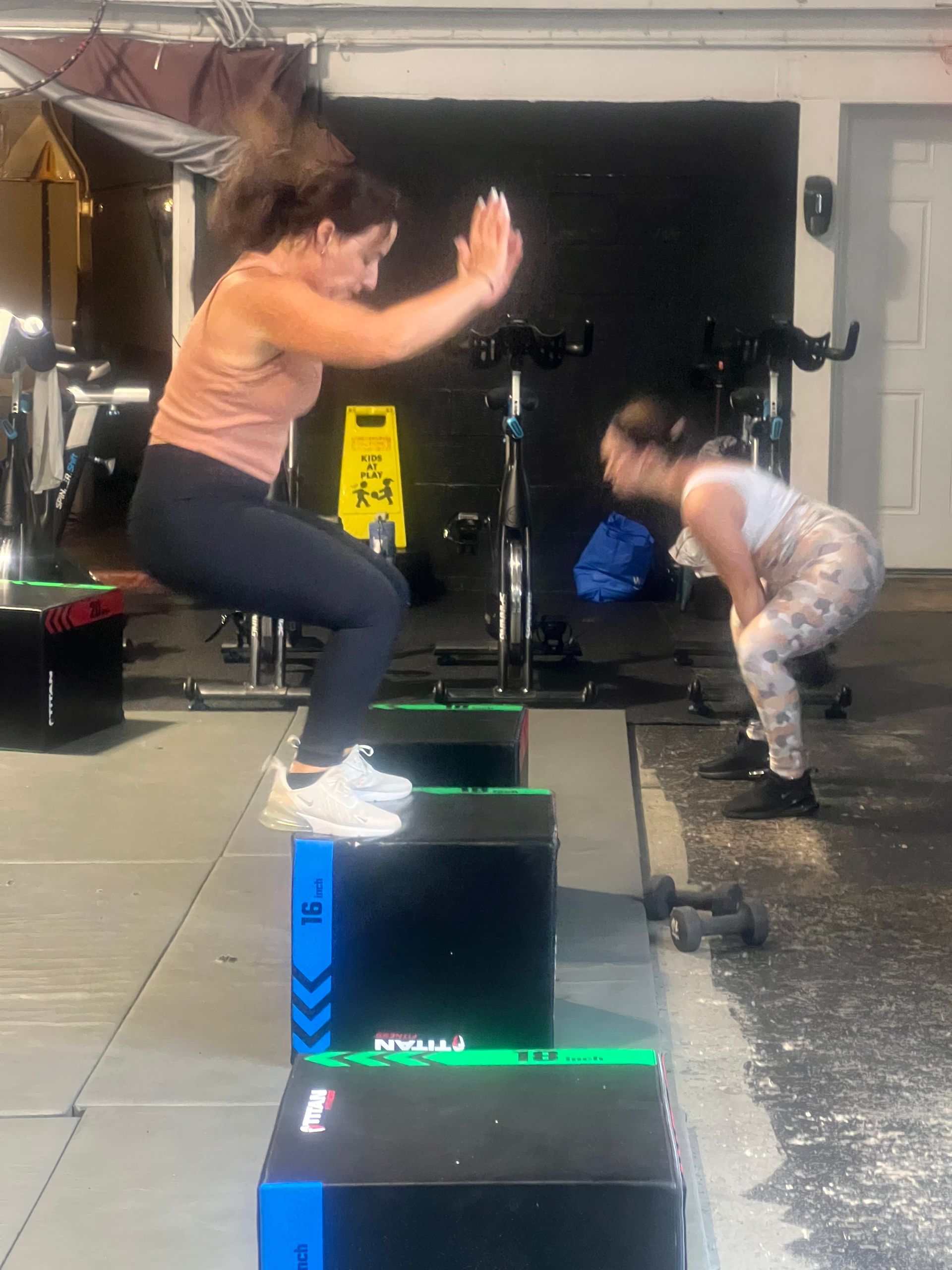 A woman is jumping over a box in a gym.