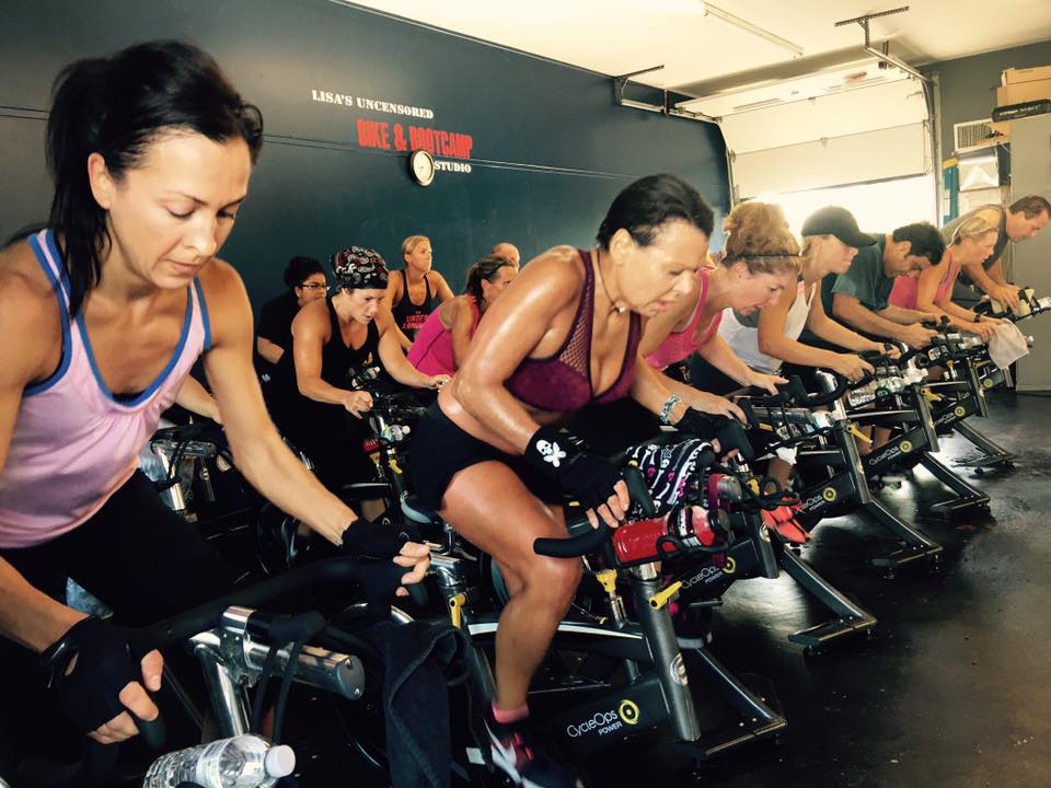 A group of people are riding exercise bikes in a gym.