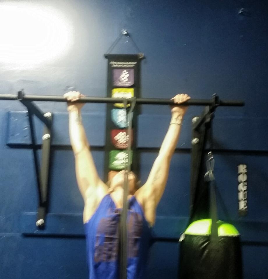 A person is doing a pull up in front of a sign that says rock