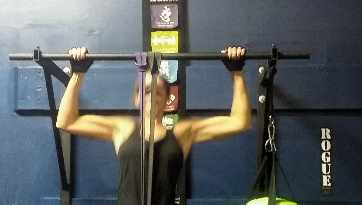 A woman is doing a pull up in a gym