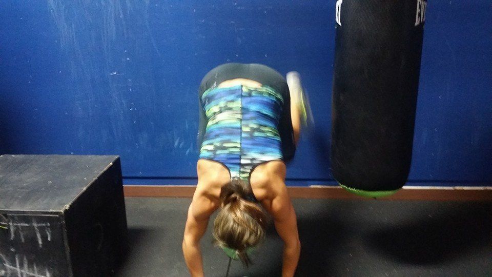 A woman is doing push ups in a gym next to a boxing bag