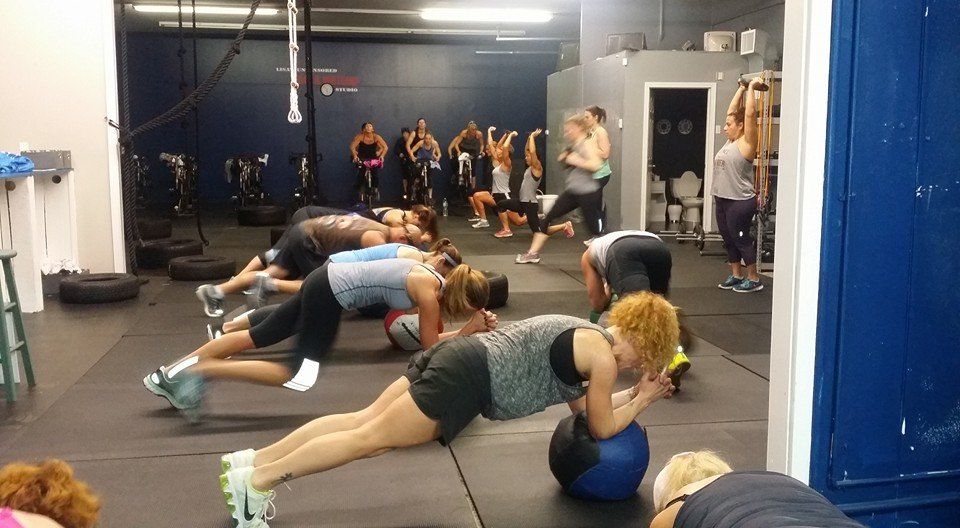 A group of people are doing push ups in a gym.