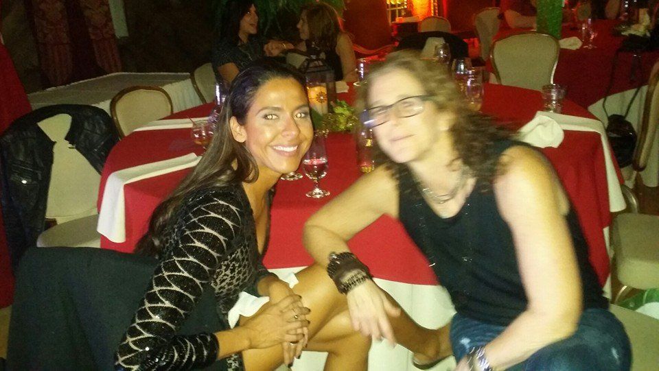 Two women are posing for a picture while sitting at a table