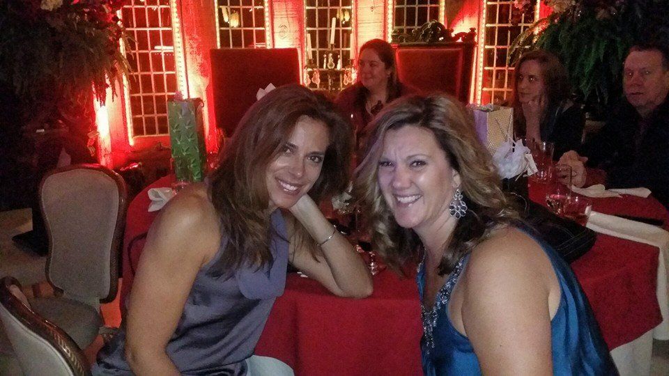 Two women are posing for a picture while sitting at a table.