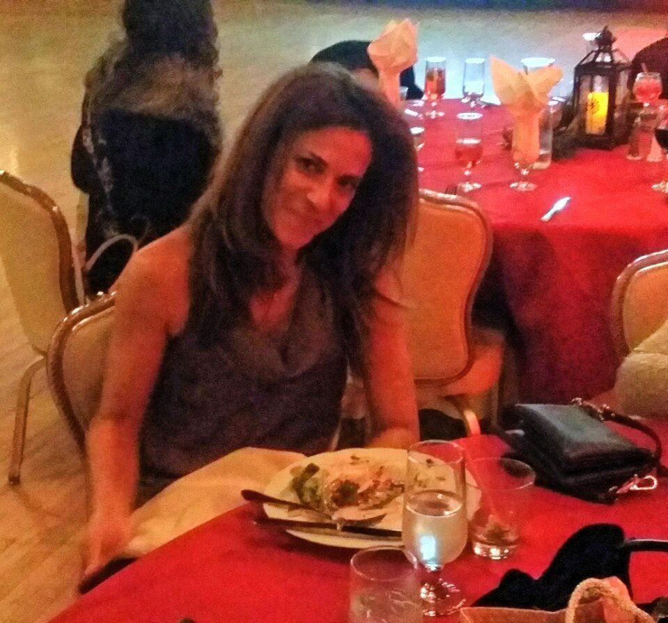 A woman sits at a table with a plate of food on it