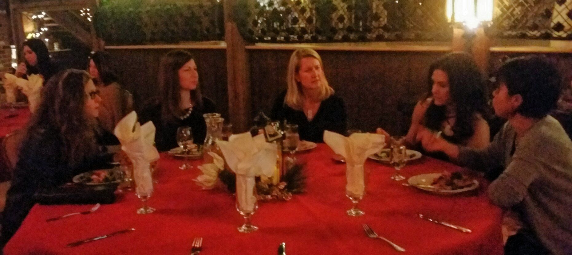 A group of women are sitting at a table with plates and wine glasses
