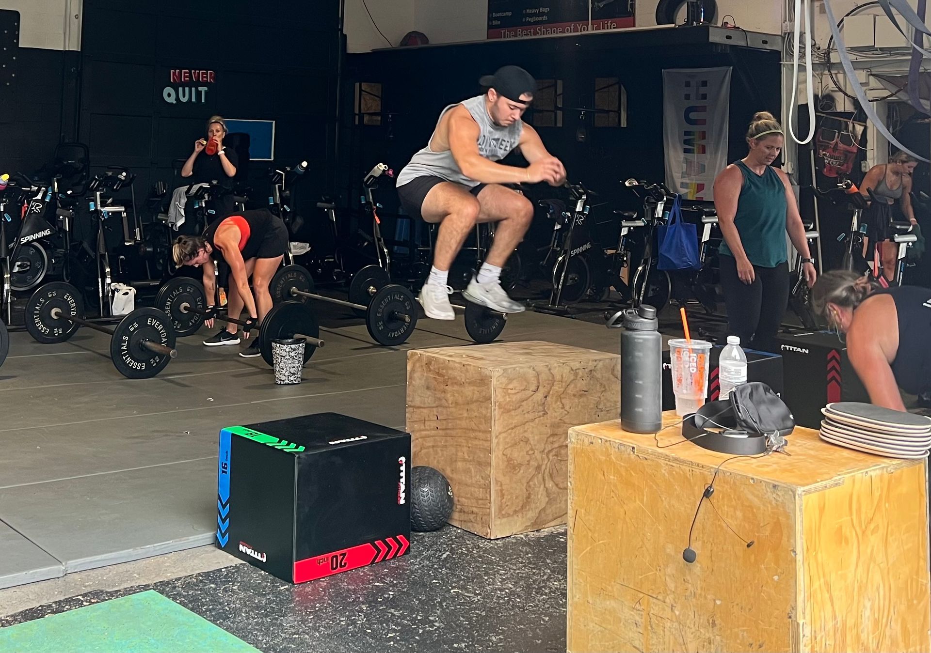 A man is squatting on a box in a gym.