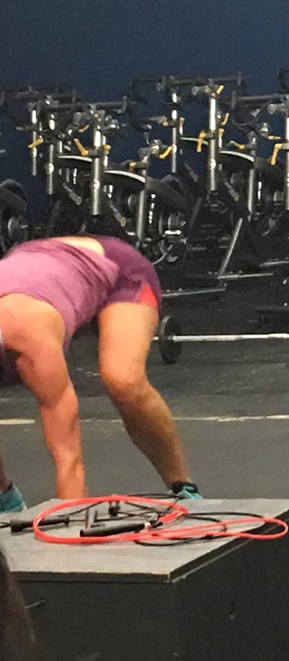 A woman is bending over on a table in a gym.