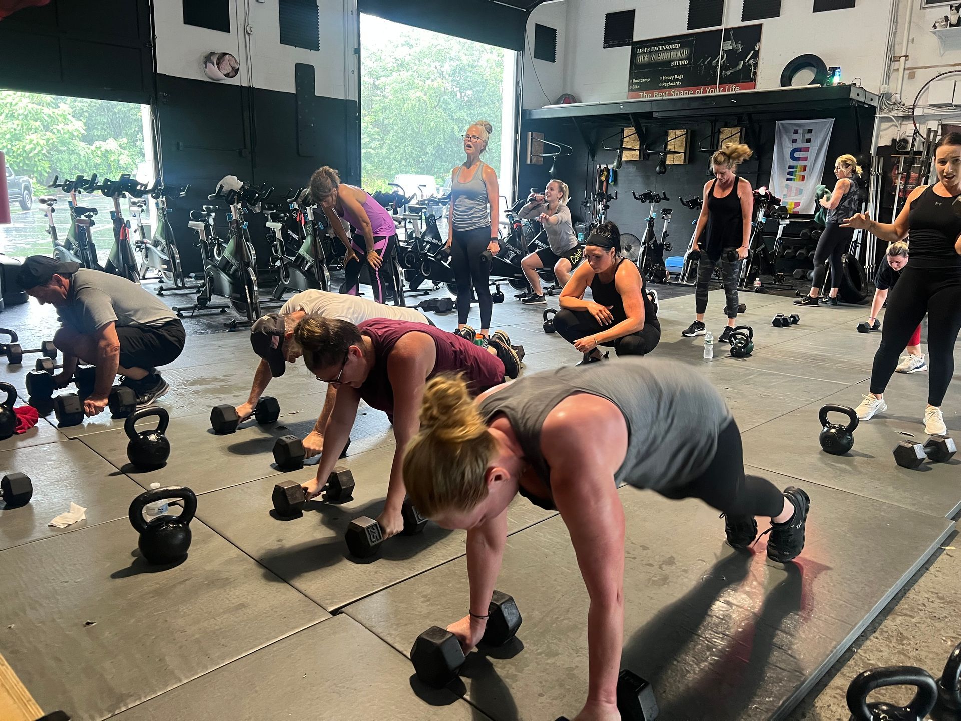 A group of people are doing push ups with dumbbells in a gym.