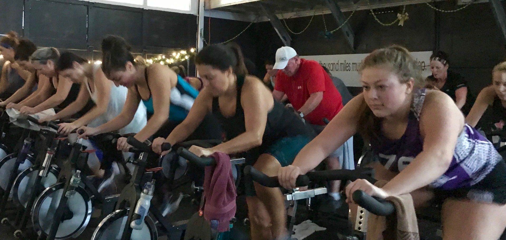 A group of women are riding exercise bikes in a gym.