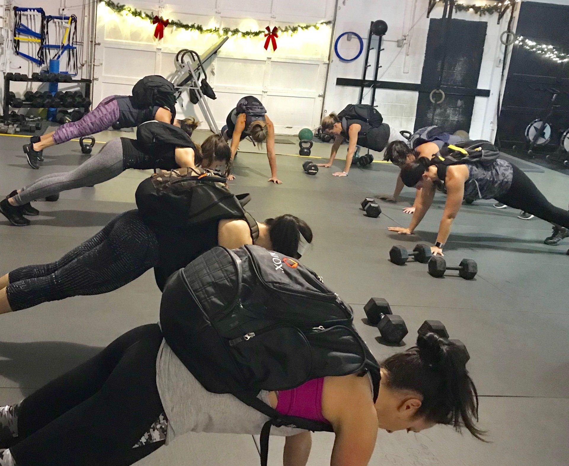 A group of women are doing push ups in a gym.
