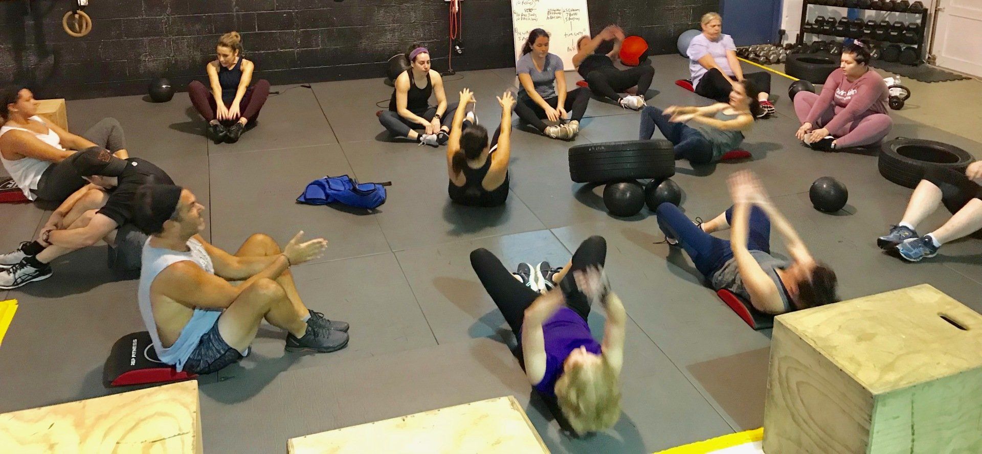 A group of people are doing exercises on the floor in a gym.