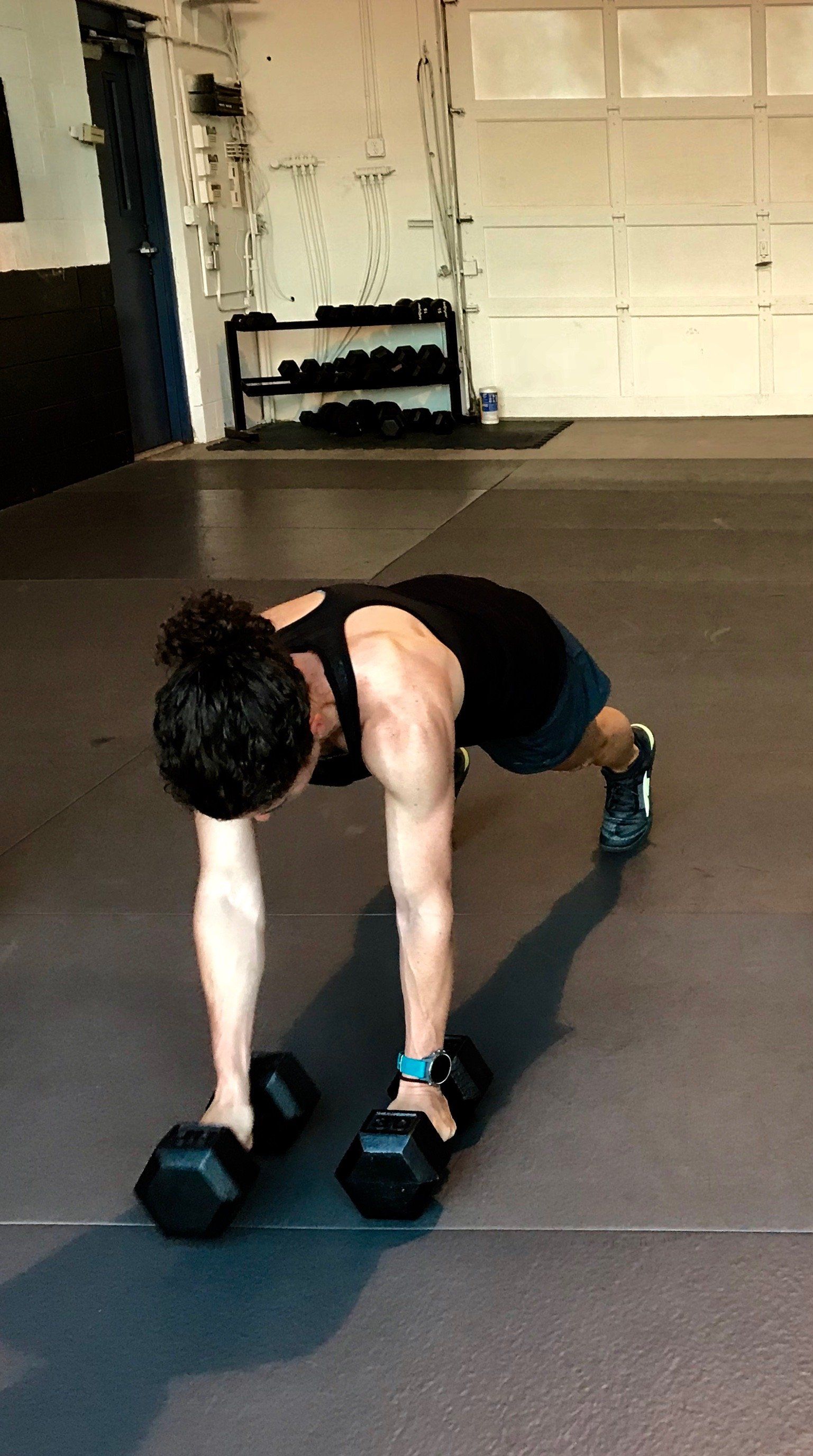 A man is doing push ups with dumbbells in a garage.