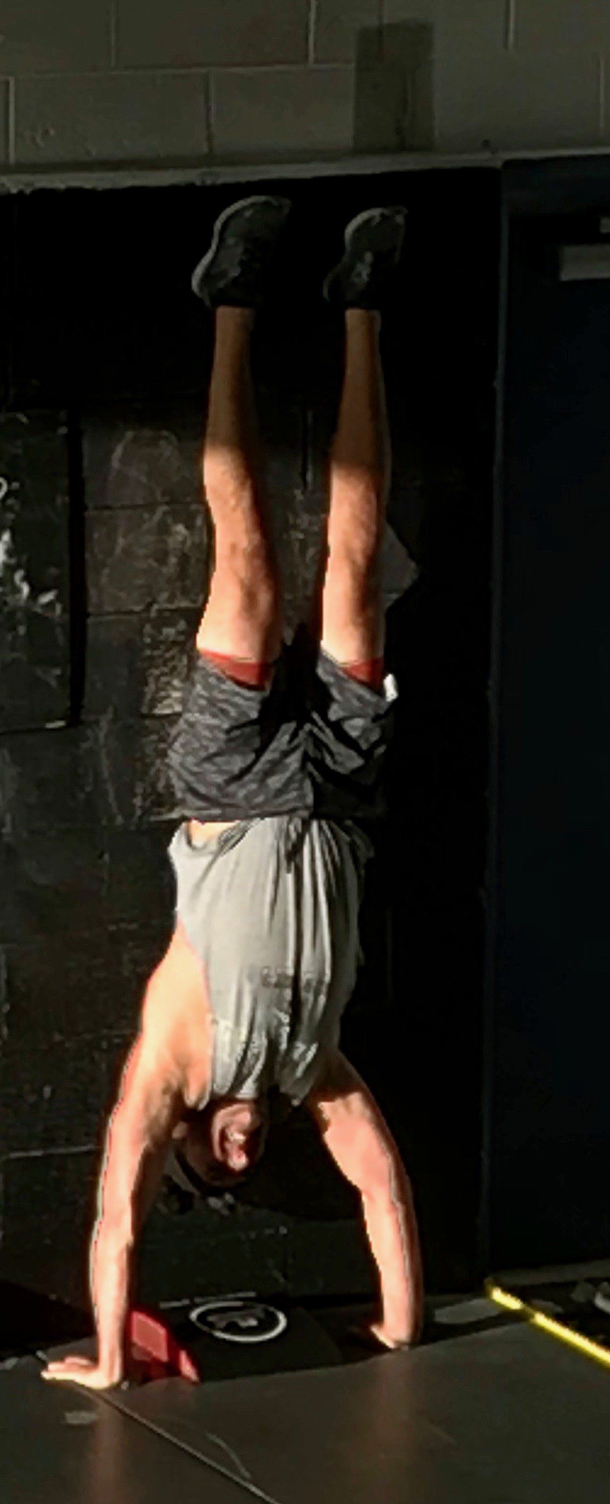 A man is doing a handstand in a gym.