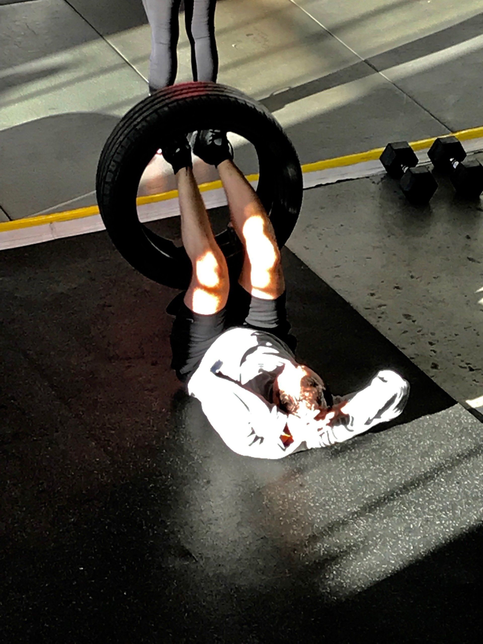 A person is doing exercises with a tire in a gym