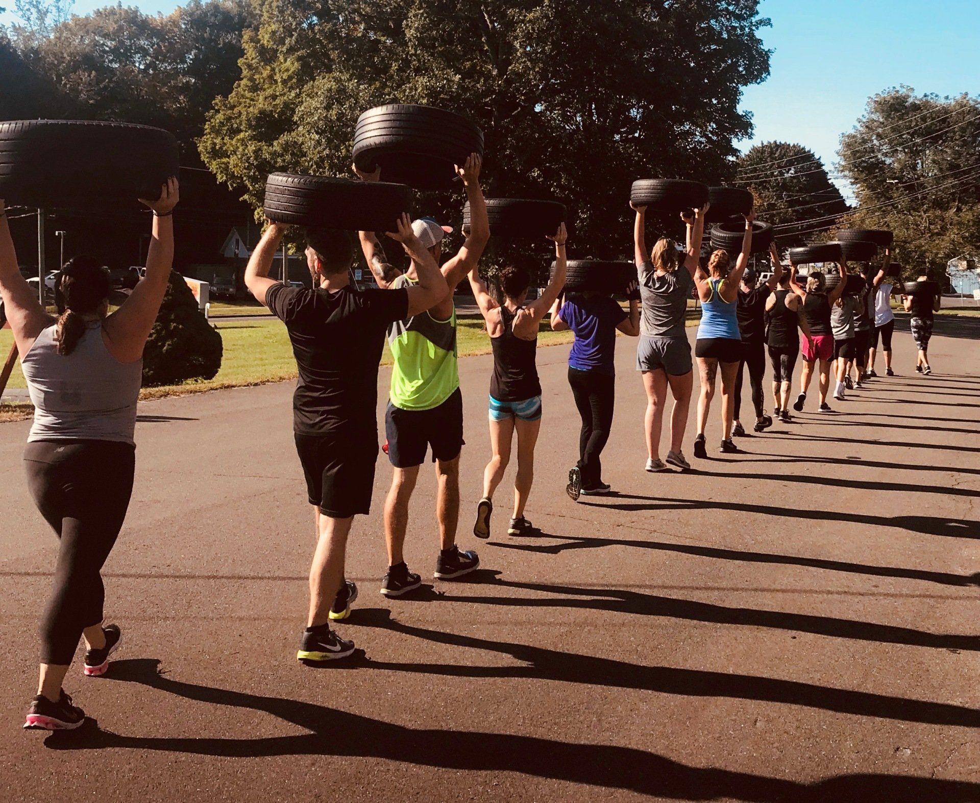 A group of people are carrying tires over their heads