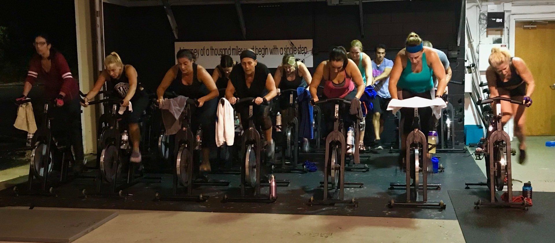A group of women are riding exercise bikes in a gym.