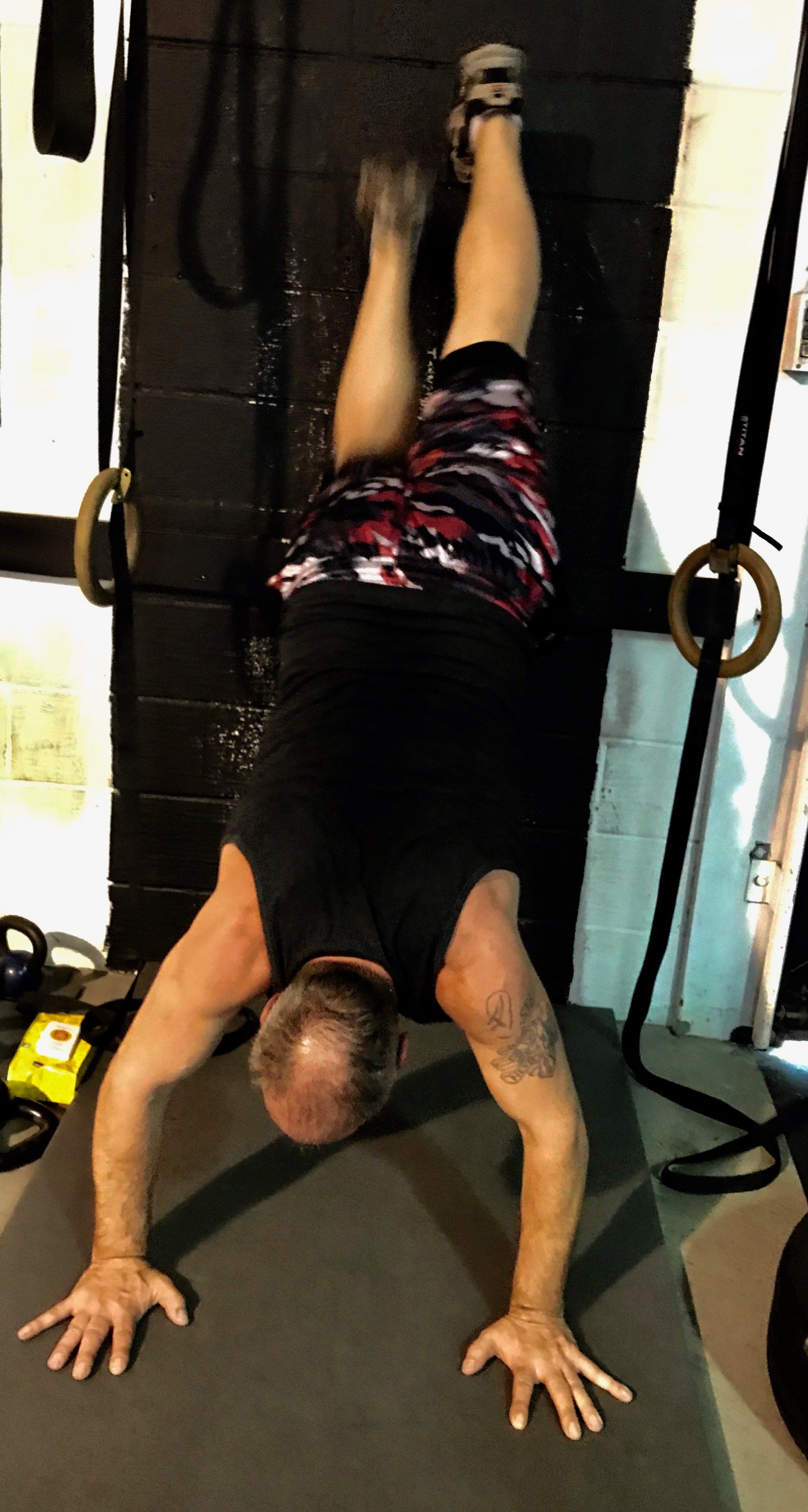 A man is doing a handstand in a gym.