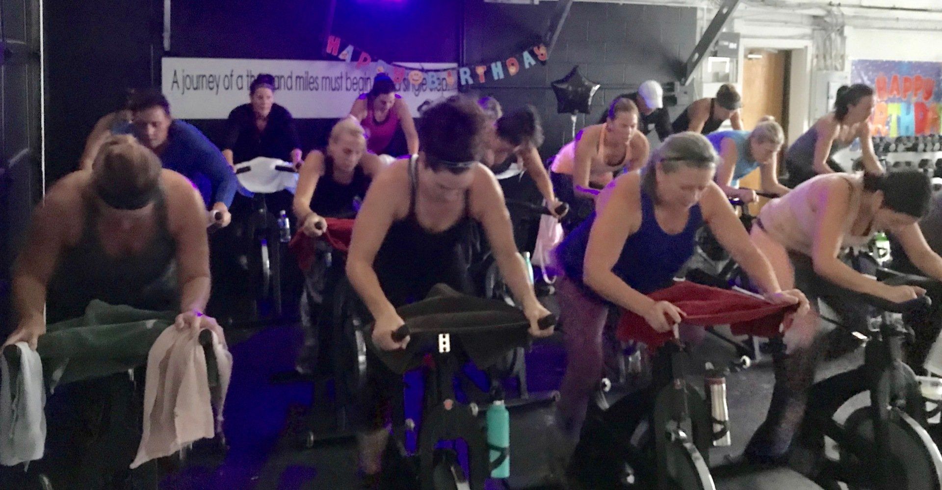 A group of people are riding exercise bikes in a gym.