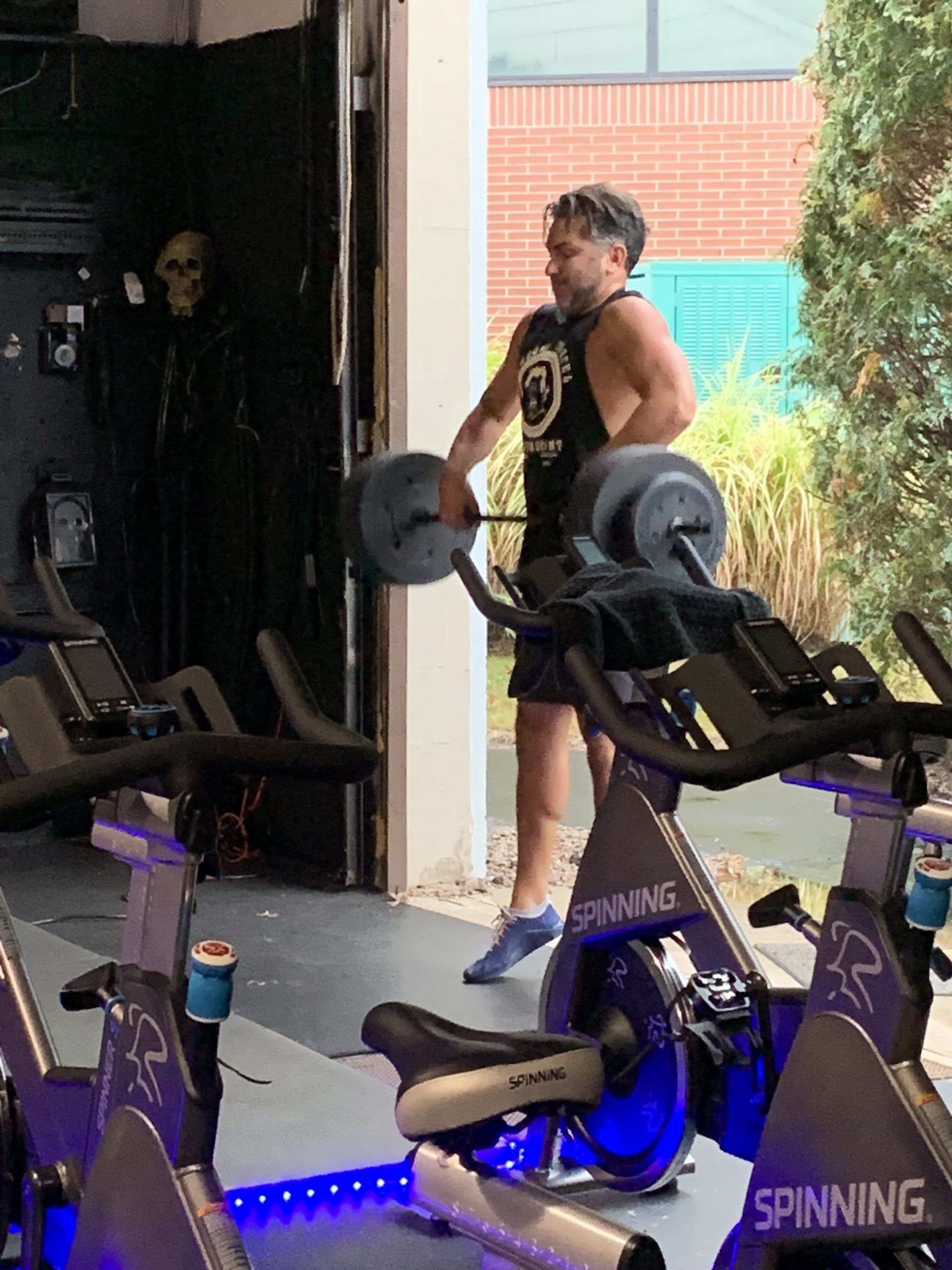 A man is standing next to a spinning bike in a gym.