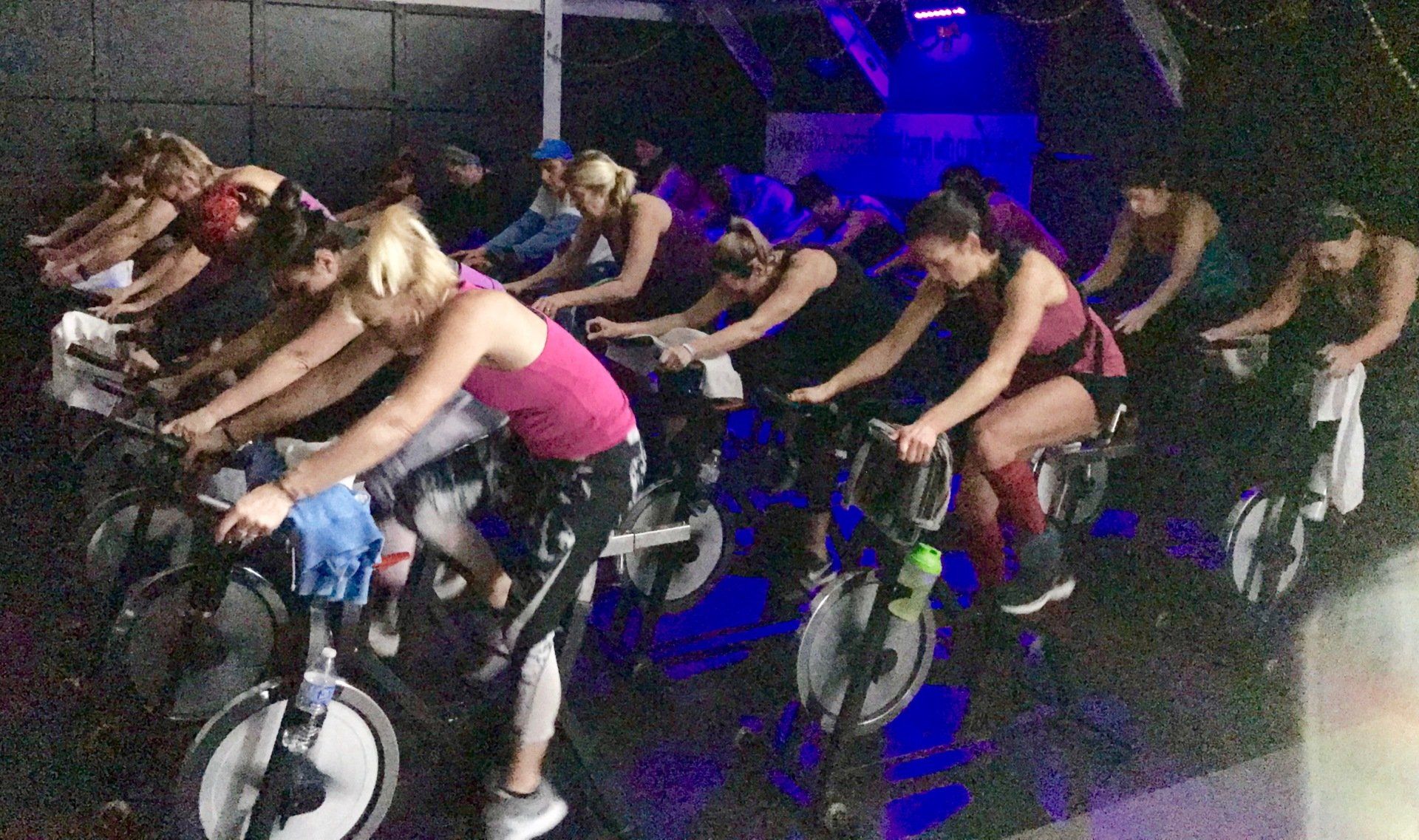 A group of people are riding exercise bikes in a gym.