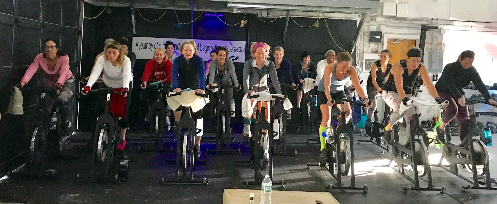 A group of people are riding exercise bikes in a gym.