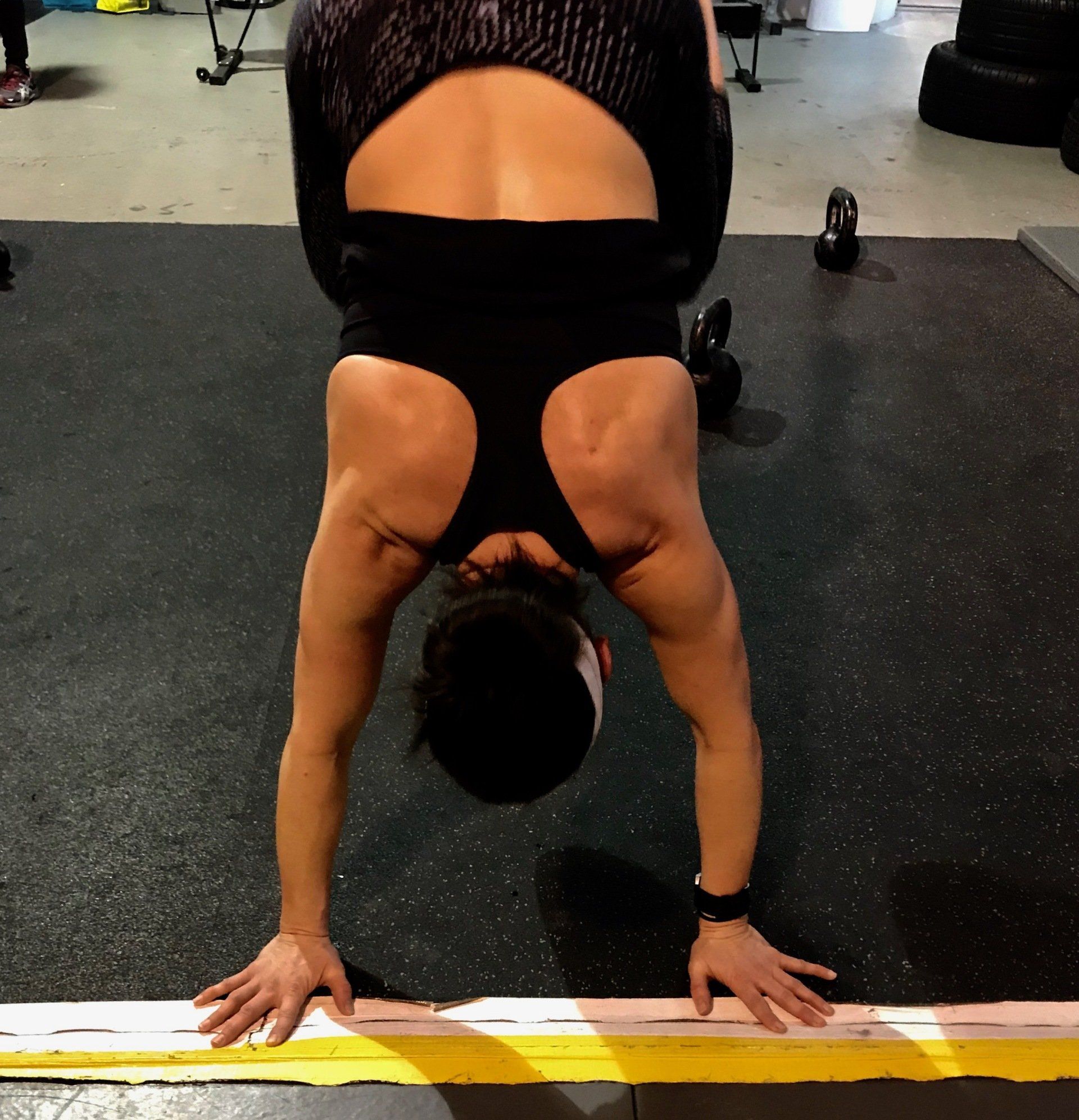 A woman is doing a handstand in a gym