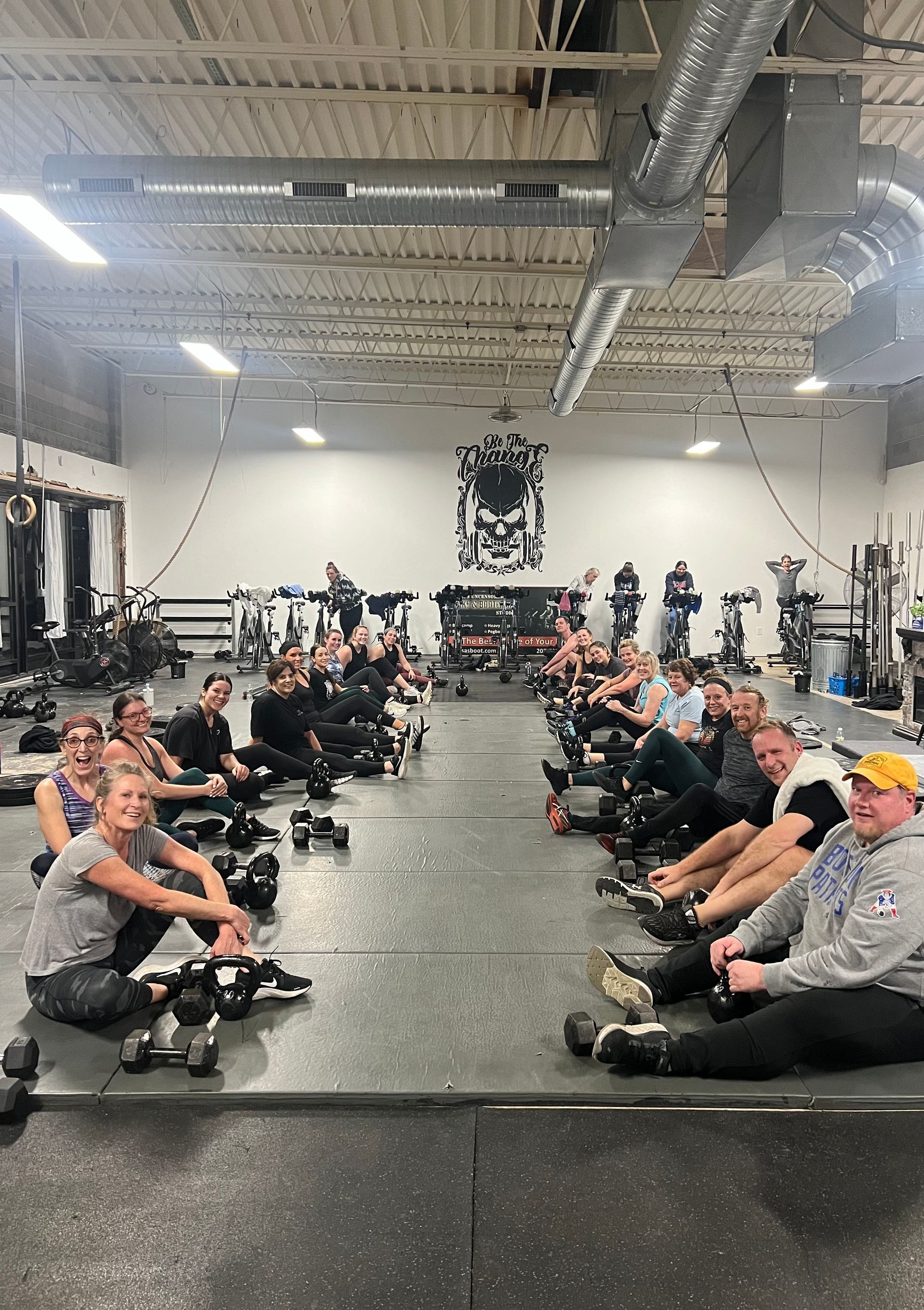 A group of people are sitting on the floor in a gym.