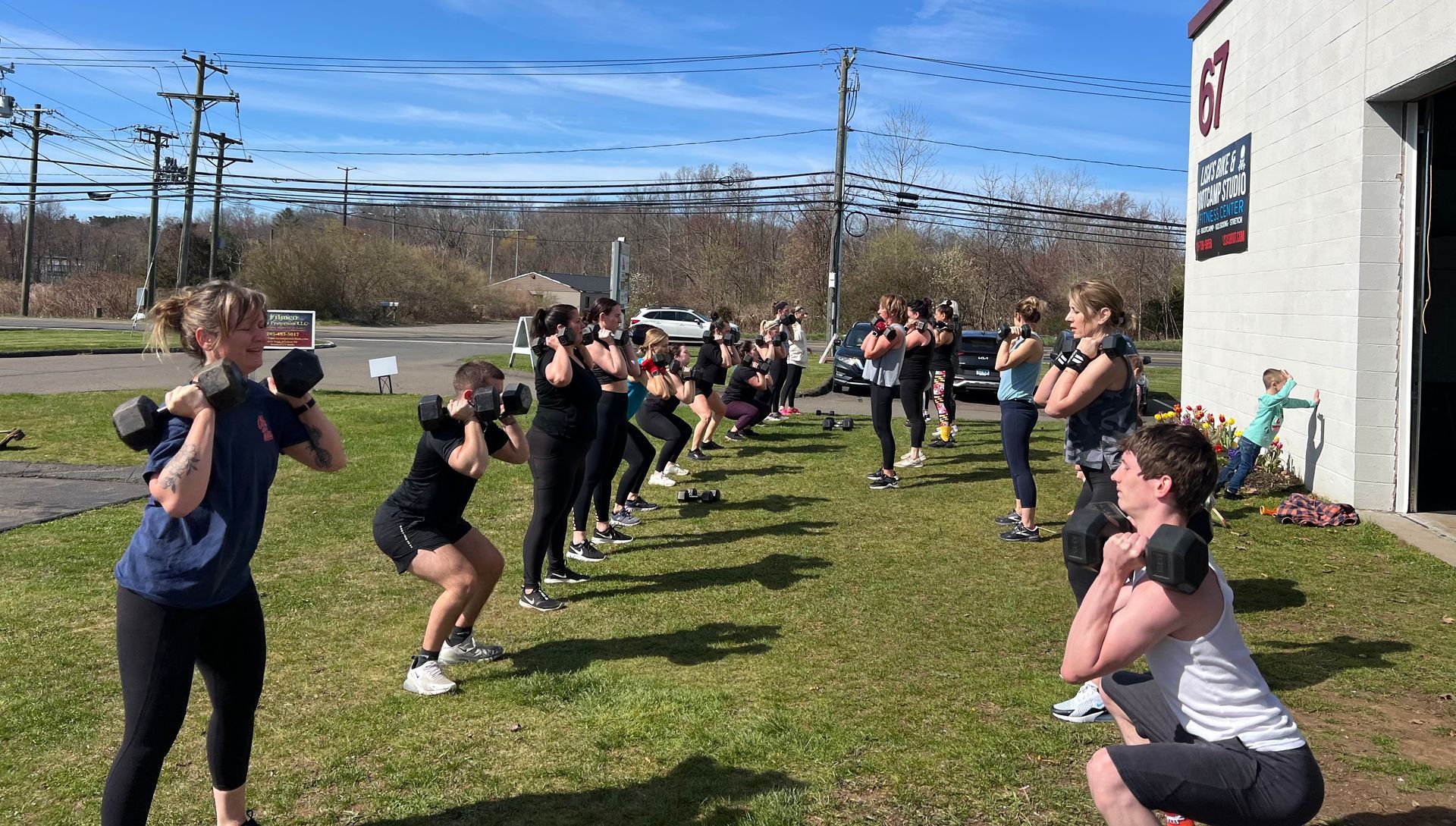 A group of people are doing squats in a grassy field.
