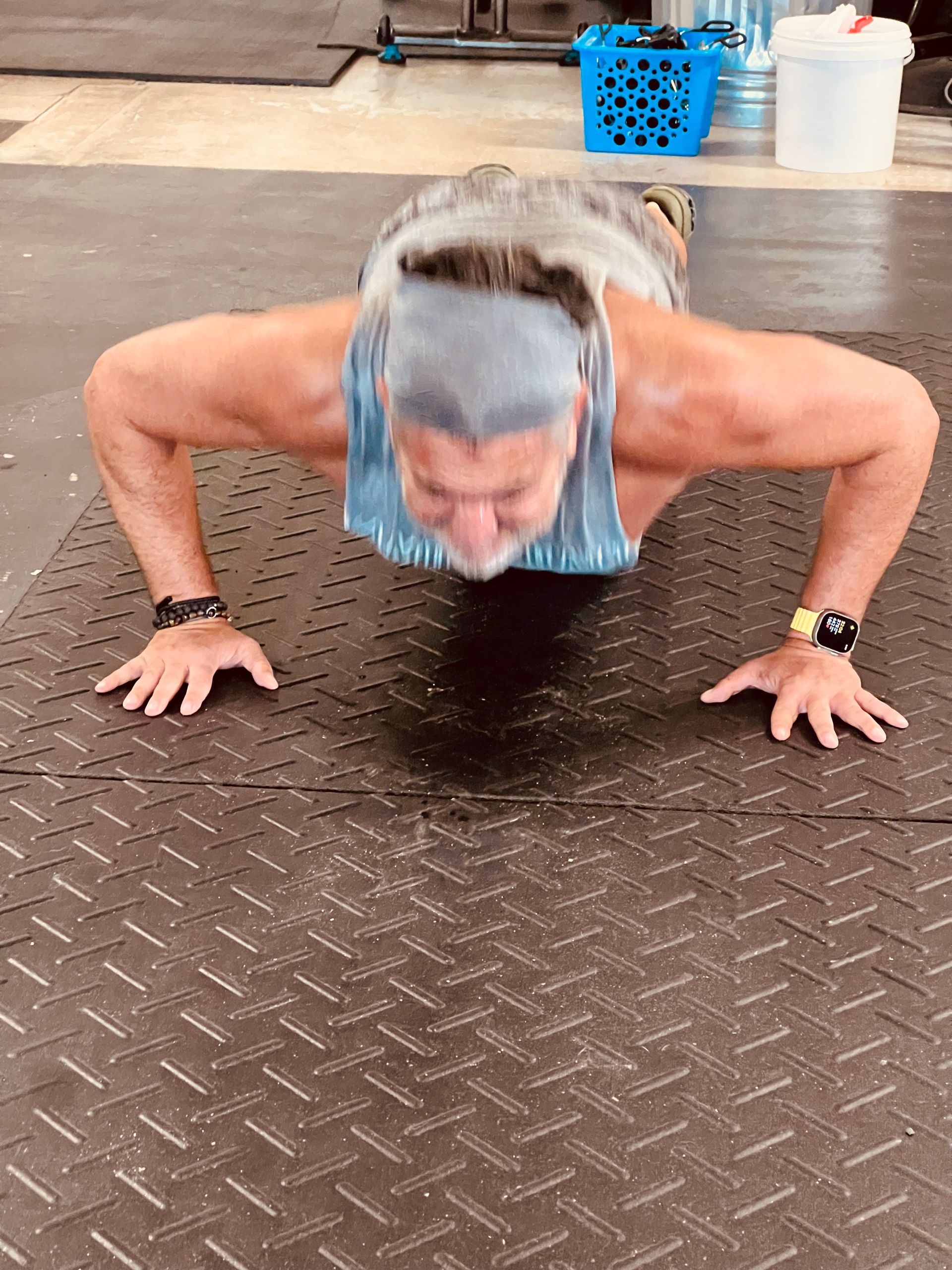 A man is doing push ups on a mat in a gym.