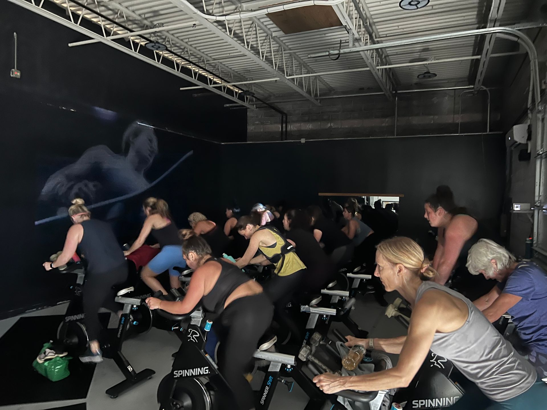 A group of people are riding spin bikes in a gym