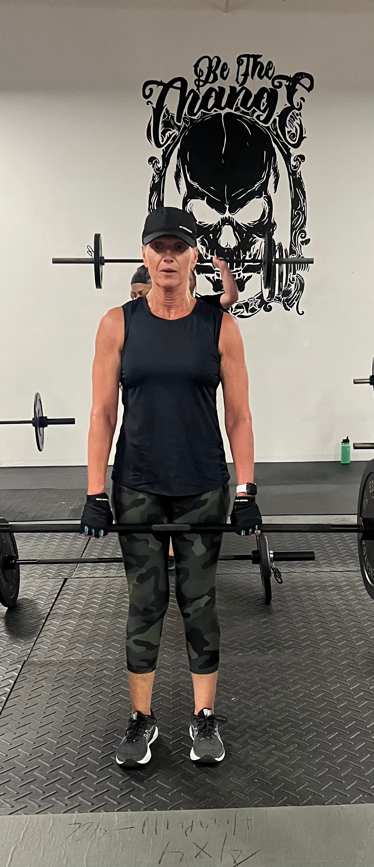 A woman is lifting a barbell in a gym.