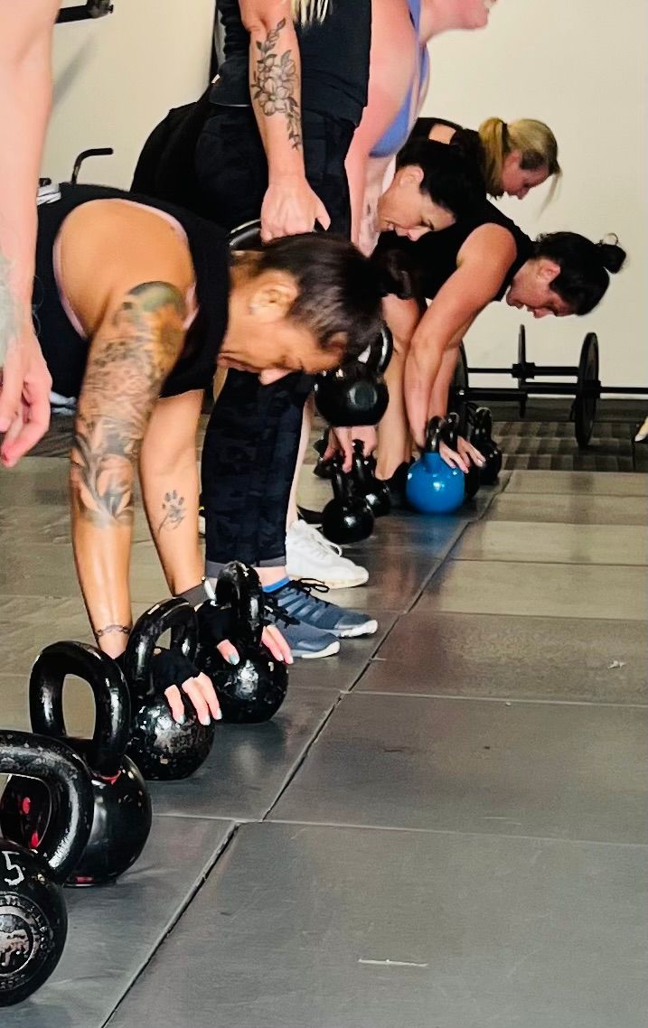 A group of people are doing exercises with kettlebells in a gym