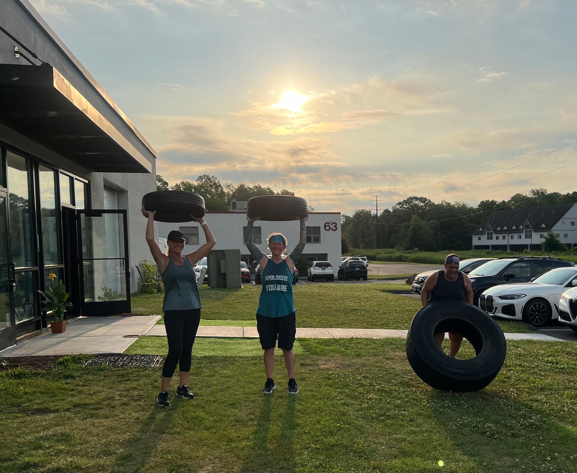 A man and a woman are carrying tires over their heads.